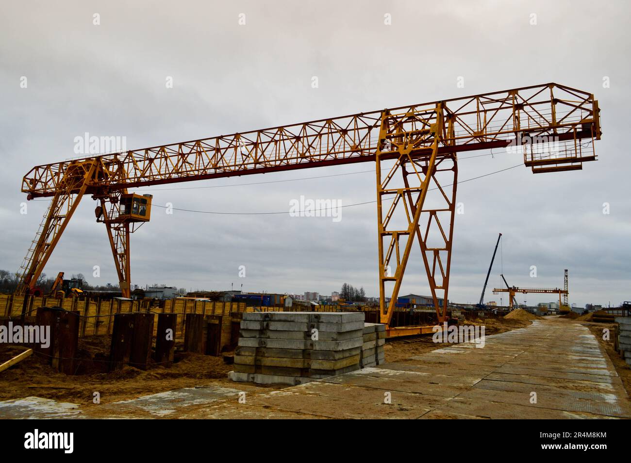 Hochschwere, gelbe Metalleisentragkonstruktion stationäre industrielle leistungsfähige Portalkran mit Brückenform auf Stützen zum Heben von Fracht auf einem m. Stockfoto