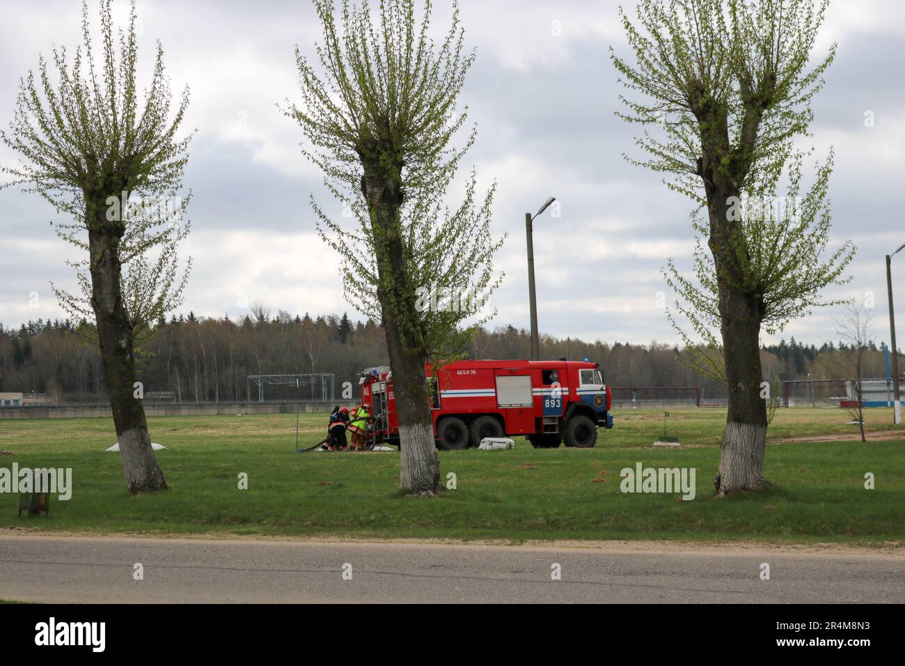 Ein großes rotes Feuerrettungsfahrzeug, ein Feuerlöscher, fährt auf einer chemischen Ölraffinerie im Hintergrund von Bäumen. Stockfoto