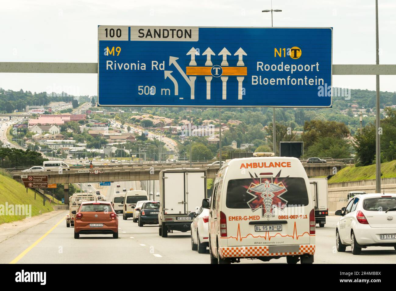 Verkehr, Fahrzeuge, Autos fahren auf einer Nationalstraße oder Autobahn unter einem blau-weißen Straßenschild in Richtung Sandton, Johannesburg, Südafrika Stockfoto