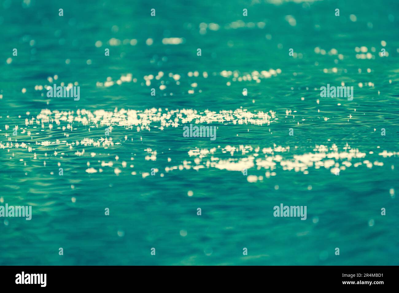 Grüne türkisfarbene Wasseroberfläche mit Lichtreflexionen wie glitzernden Diamanten in Pflastern als abstrakter Naturhintergrund, Tapete oder Hintergrund Stockfoto