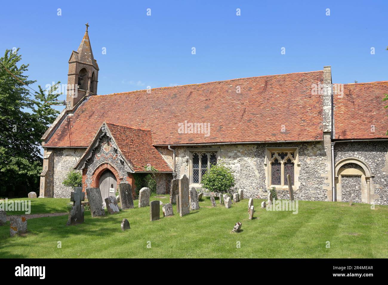 St. Nicholas Church, Ipsden, South Oxfordshire, England, vom Friedhof aus gesehen, inmitten eines blauen Frühlingshimmels Stockfoto