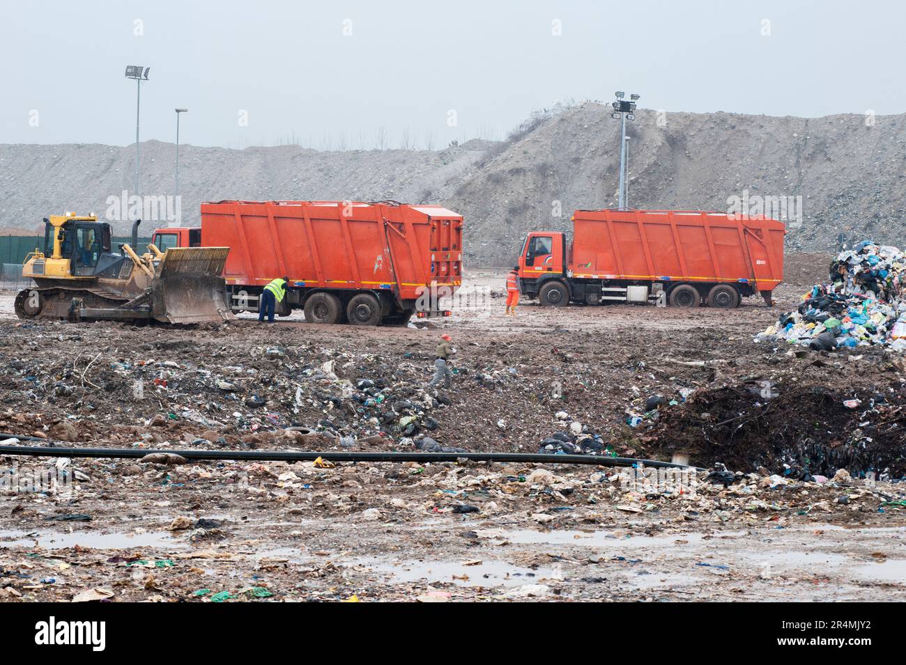 Siedlungsabfälle entsorgen. Arbeiter mit Lkw und Bulldozern bei der Arbeit auf Mülldeponien. Stockfoto