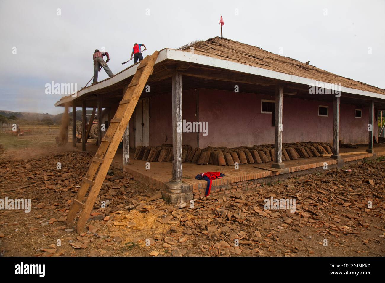 Männer schaufeln Dreck vom Dach eines Gebäudes und stehen immer noch nach dem verheerenden Erdbeben. Stockfoto