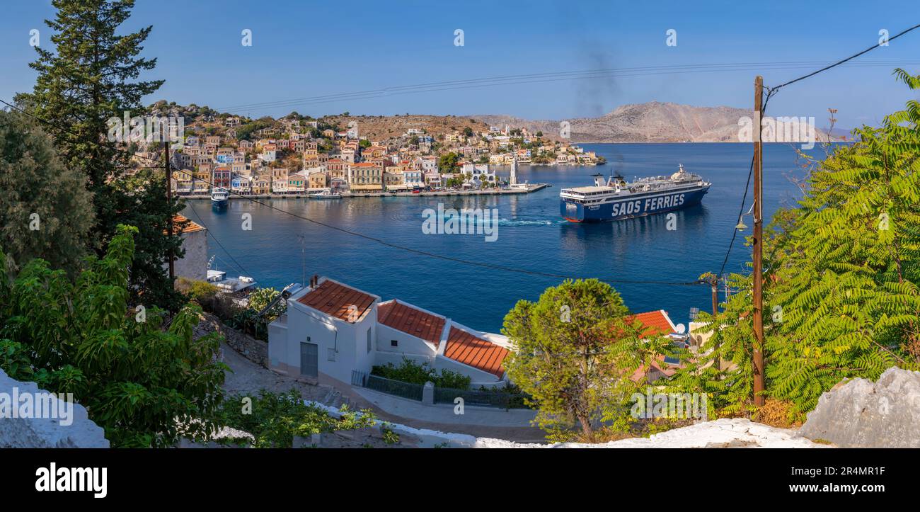 Blick auf die Fähre, die den Hafen von der erhöhten Position in Symi, Symi, Dodekanes, griechischen Inseln, Griechenland, Europa Stockfoto