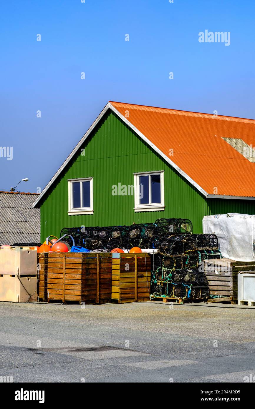 Olberg; Olbergstranden; Raege; Norwegen; Mai 20 2023; Traditionelles Grün gemaltetes Haus mit Hummer und Krabbenbechern, die vor Einem klaren blauen Sk gestapelt sind Stockfoto