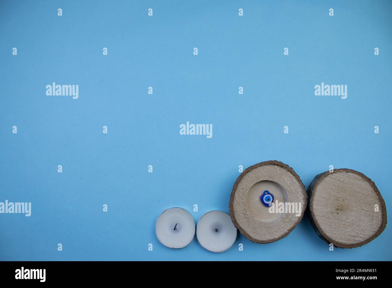 Kleine Stämme, böse Augenperlen und kleine Kerzen auf dem blauen Hintergrund, fotografiert von oben. Stockfoto