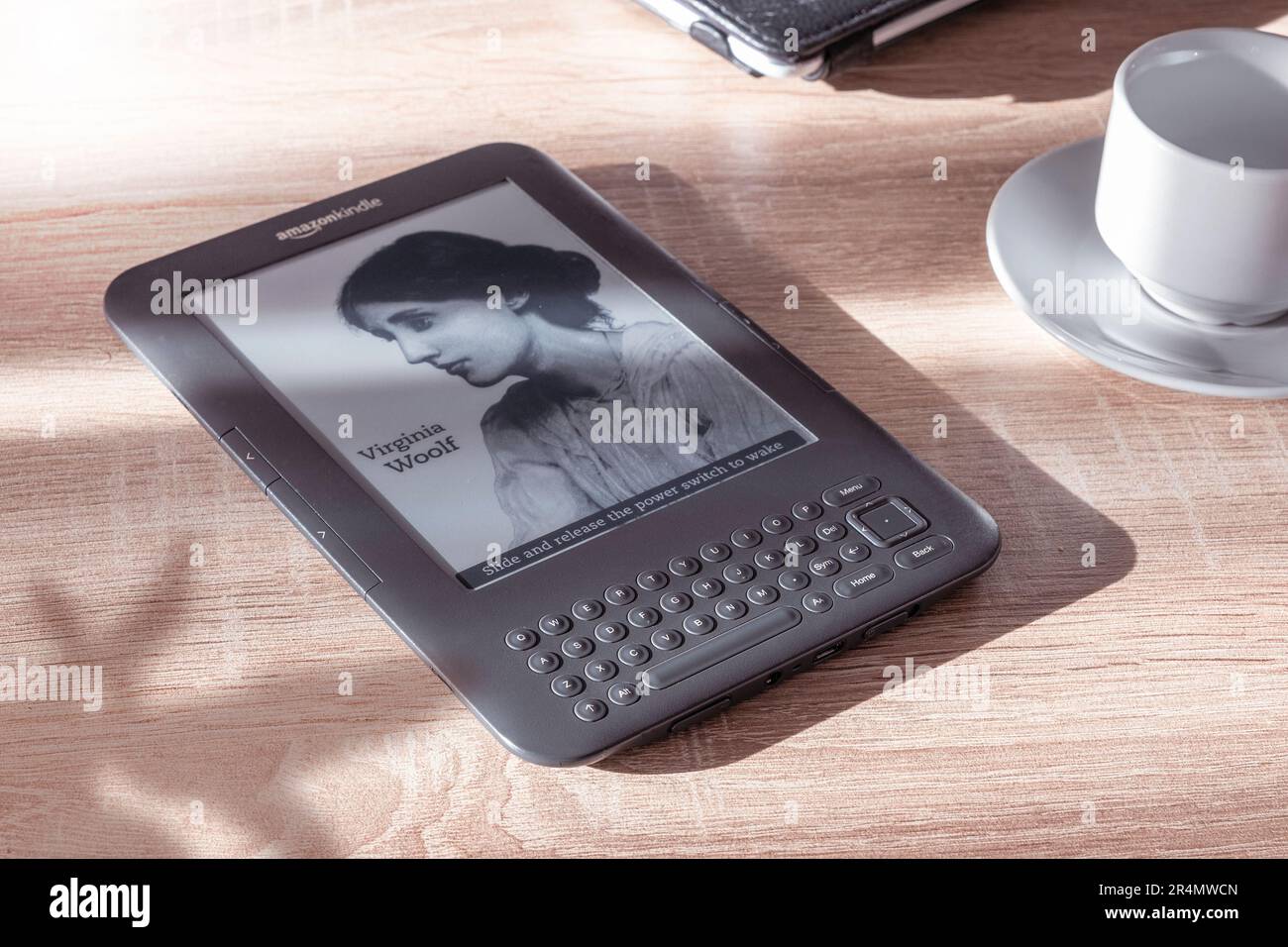 Amazon Kindle eBook Reader auf einem Holztisch neben einer Pflanze und einer Tasse Kaffee. Leerer Kopierbereich für Editortext. Stockfoto