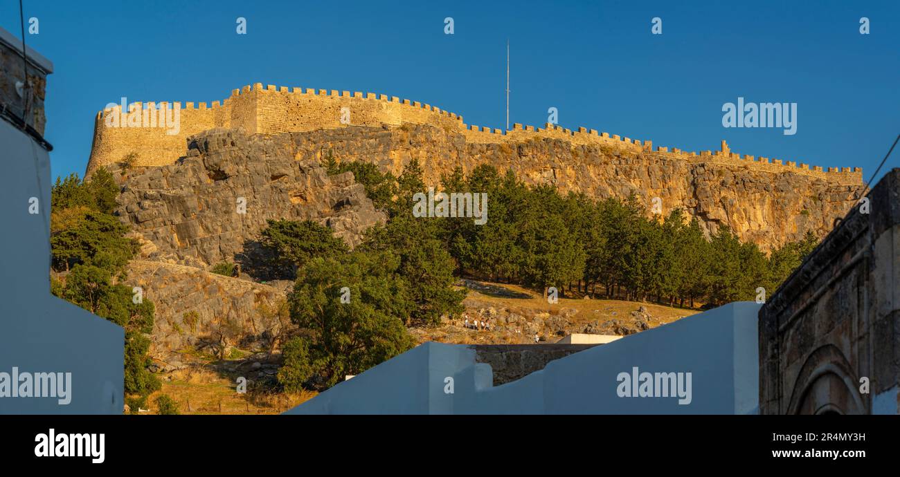 Blick auf Lindos Akropolis von der weiß getünchten Straße in der Stadt bei Sonnenuntergang, Lindos, Rhodos, Dodekanese Inselgruppe, griechische Inseln, Griechenland, Europa Stockfoto