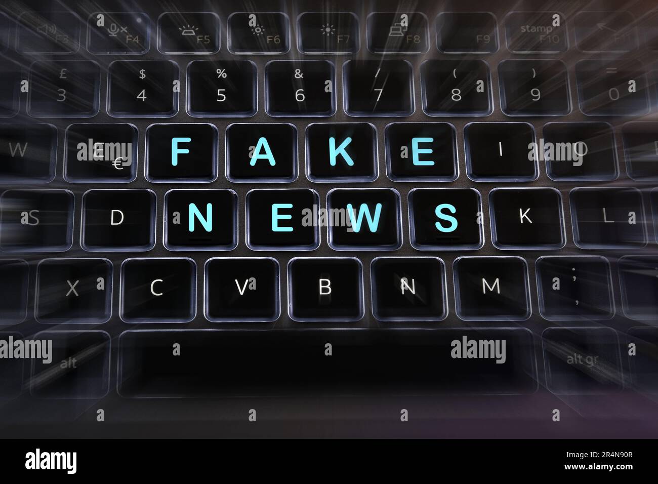 Gefälschte Nachrichten mit Unschärfe-Effekten auf den Tasten einer hintergrundbeleuchteten Laptop-Tastatur. Stockfoto