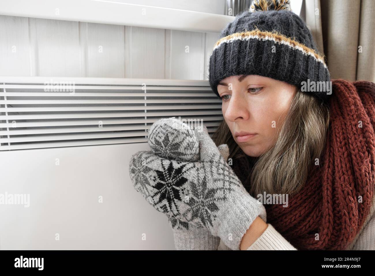 Junge gefrorene Frau, die einen Pullover trägt, schüttelt und friert bei Winterkälte mit Schockausdruck im Gesicht. Das Mädchen wärmt die Hände mit Atem über Elle auf Stockfoto