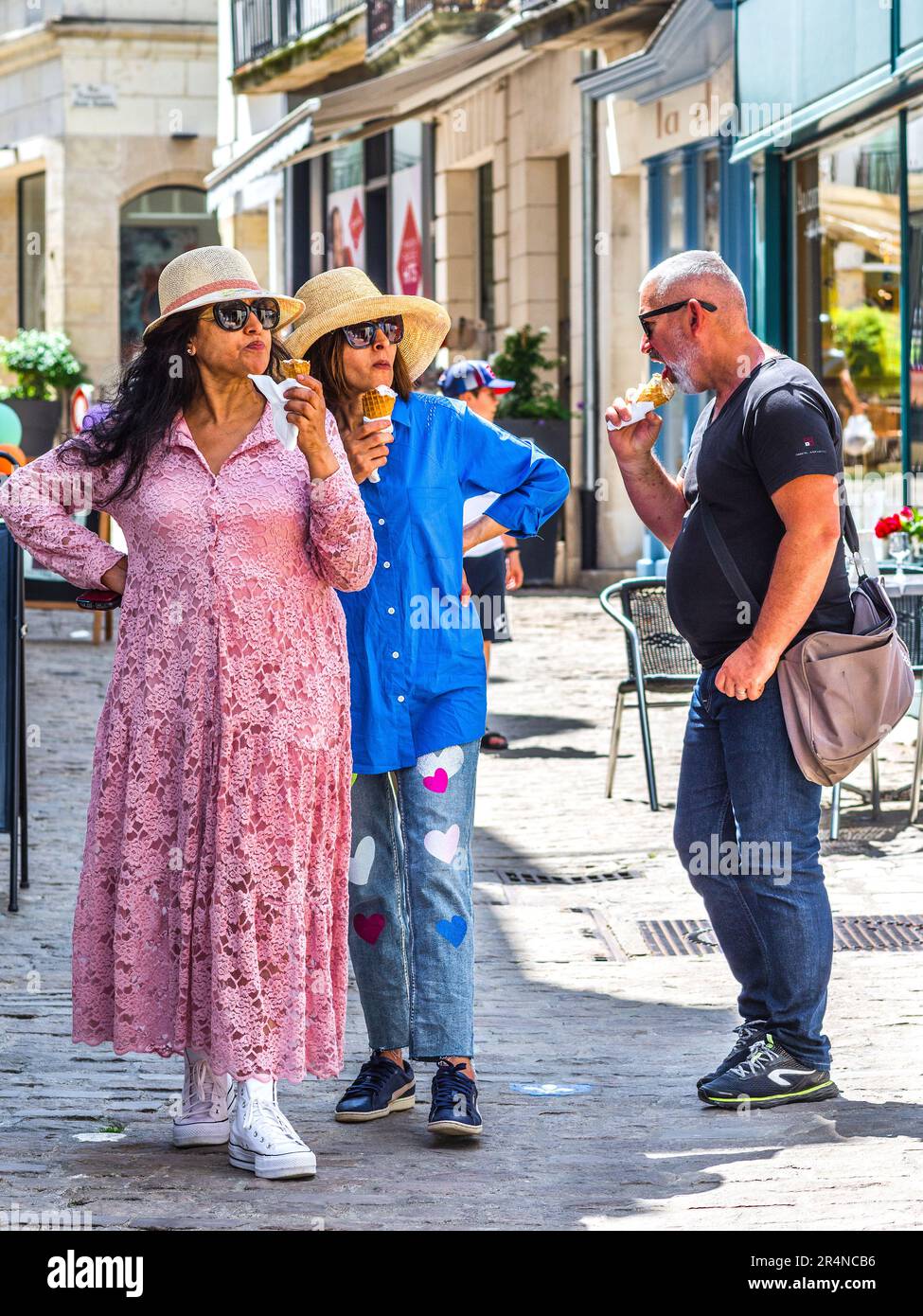 Drei Touristen, die Eiskrem-Kornets in der Straße der Stadt essen - Loches, Indre-et-Loire (37), Frankreich. Stockfoto