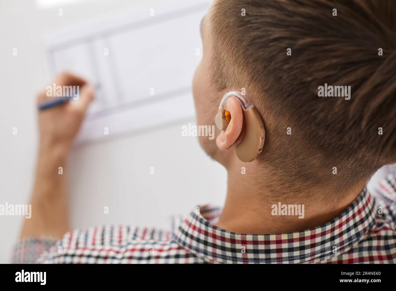 Nahaufnahme eines Menschen mit Hörgerät, der auf Papier malt Stockfoto