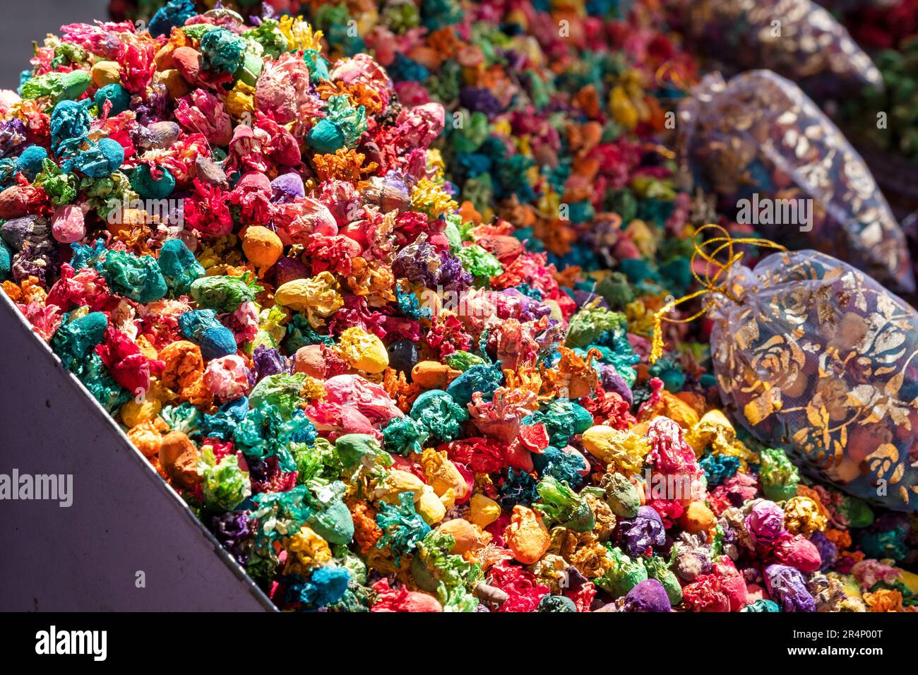 Ein Nahbild von sonnenbeleuchteten, gehäuften, bunten, getrockneten Blumenköpfen vor einem Kräutermarkt auf dem Mellah Market, Marrakesch, Marokko. Stockfoto
