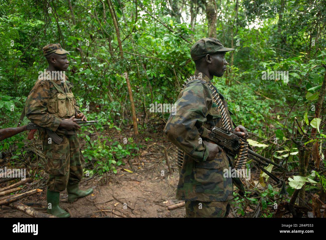Zwei Soldaten der ugandischen Armee (UPDF), der linke mit einem AK47-Sturmgewehr bewaffnet, der rechte mit einem PKM-Gürtelgewehr. Sie stehen in einem Versteck im Regenwald, das einst von Mitgliedern der Widerstandsarmee der Lords besetzt war, in der Zentralafrikanischen Republik Stockfoto