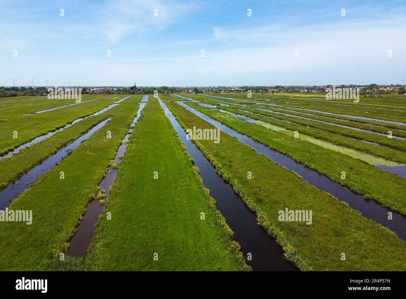 Atemberaubender Blick aus der Vogelperspektive auf die weite, offene niederländische Polderlandschaft mit parallelen wassergefüllten Gräben und Kanälen Stockfoto