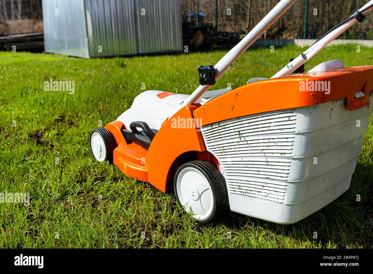 Ein kleiner, motorisierter Elektromäher steht auf dem Rasen und ist orange gefärbt. Stockfoto