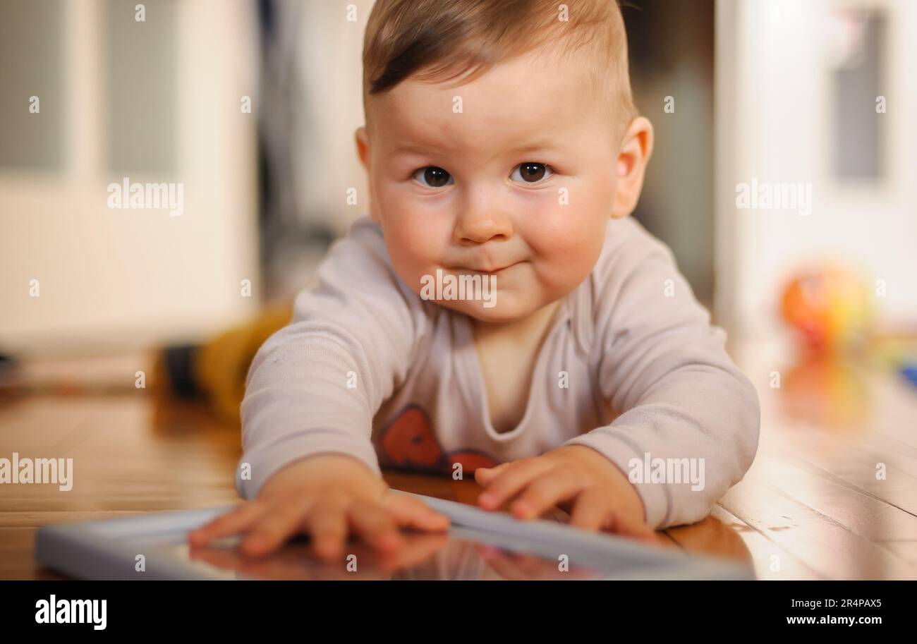 Der süße Junge krabbelt auf dem Hausboden herum, erkundet die Welt und lernt, sich zu bewegen. Liebe und Familiengefühle Stockfoto