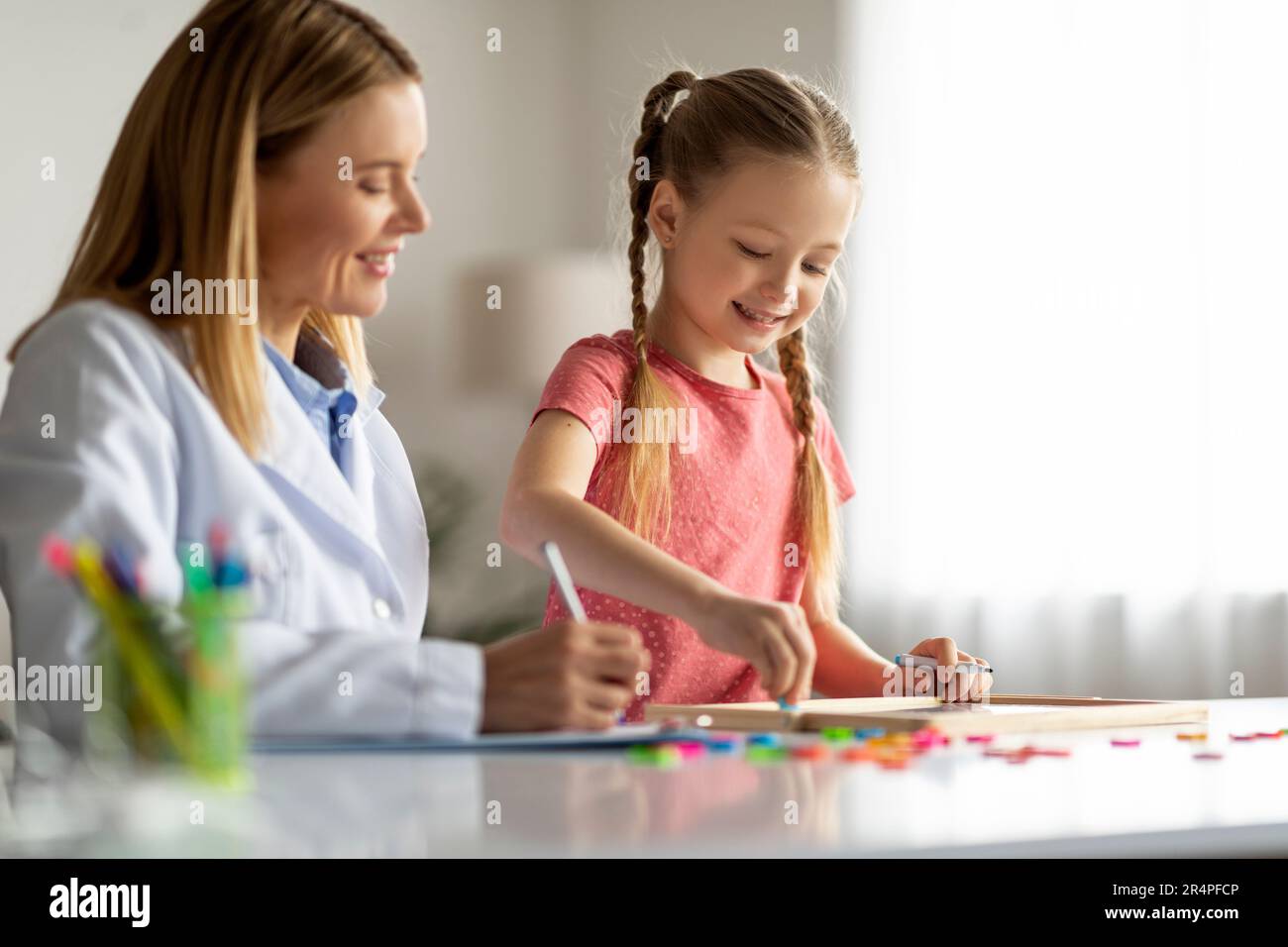 Little Girl Malerei Auf Dem Reißbrett Während Des Meetings Mit Dem Spezialisten Für Kinderentwicklung Stockfoto
