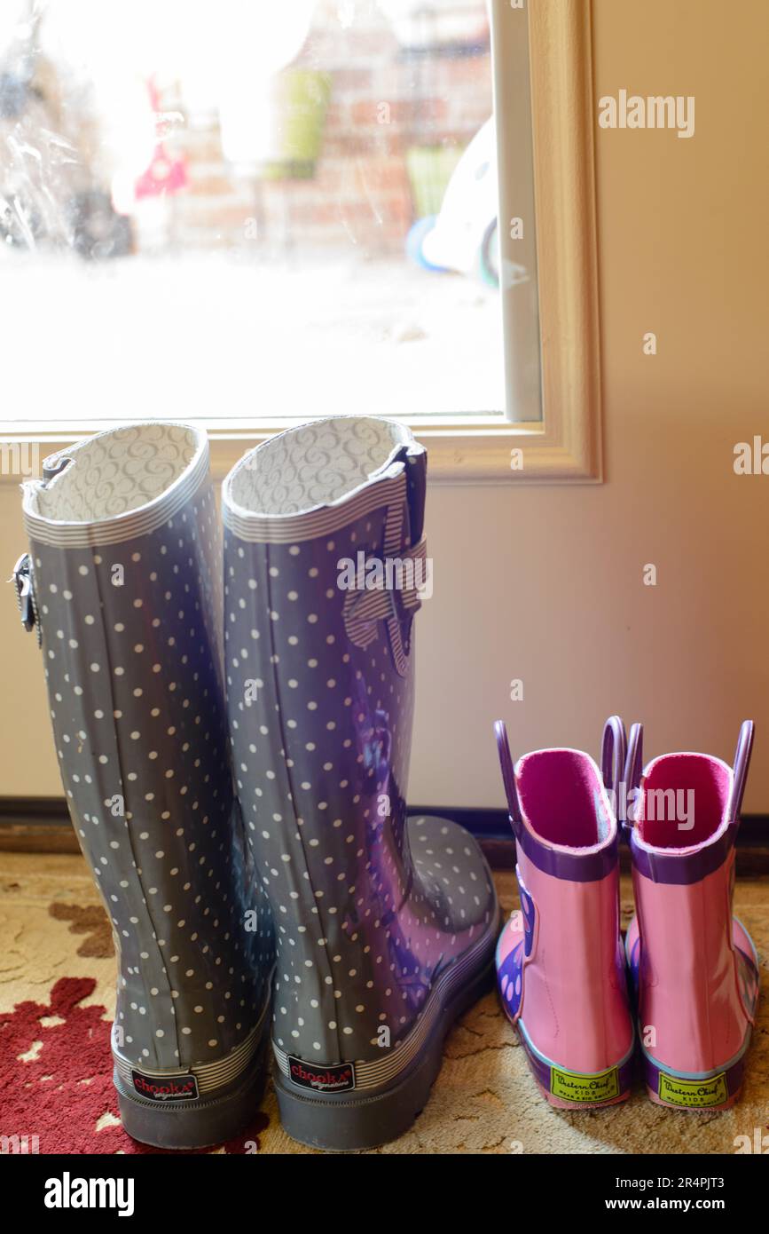 Zwei Paar Gummistiefel für Mutter und Tochter, nebeneinander an der Hintertür. Stockfoto
