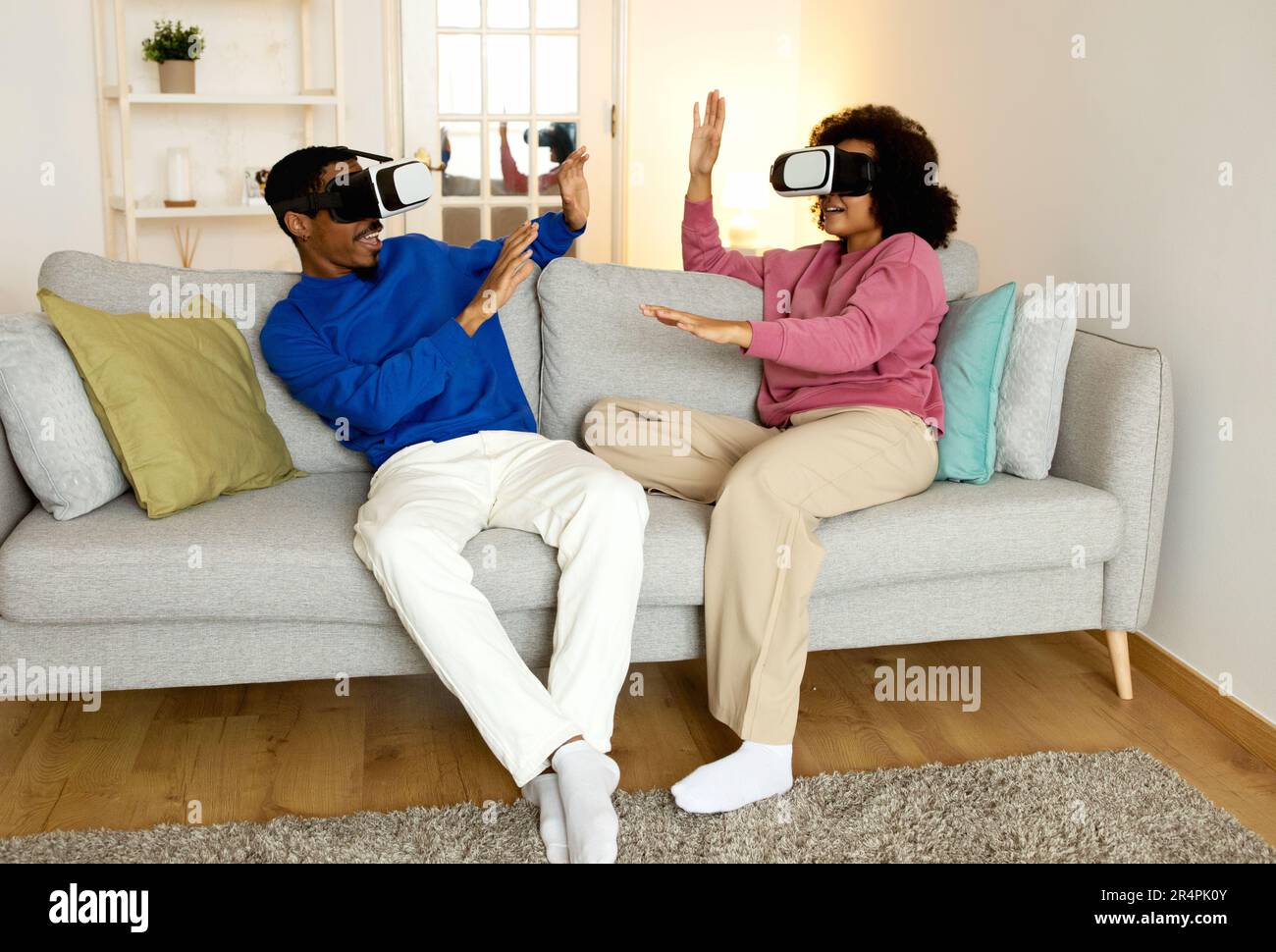 Schwarzes Paar mit VR-Headsets, das zu Hause Virtual Game spielt Stockfoto