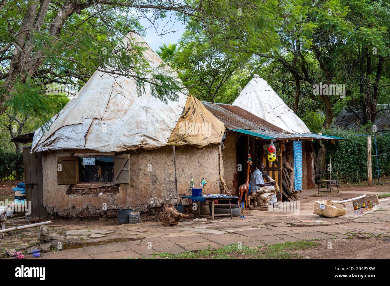 Ein Einheimischer sitzt vor seiner traditionellen runden Schlammhütte. Kenia, Afrika. Stockfoto