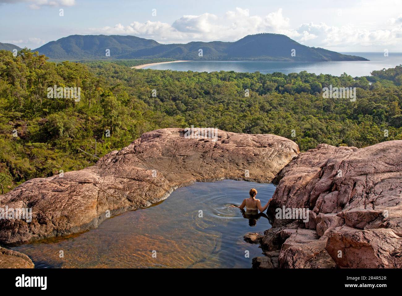 Frau schwimmt in einem Pool auf der Spitze von Zoe Falls, Hinchinbrook Island Stockfoto