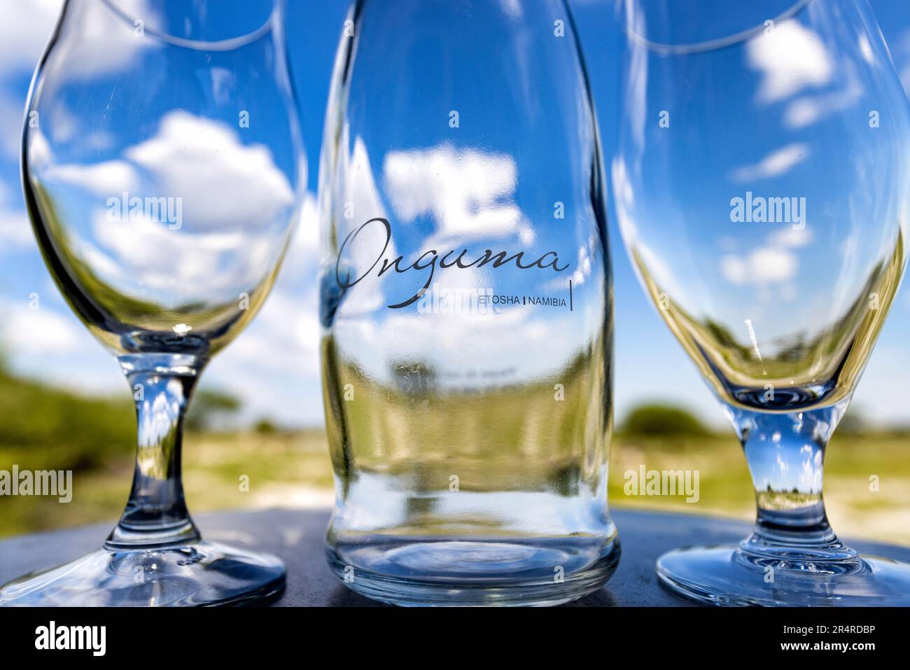Nahaufnahme von Onguma Flasche und Gläsern mit Fisher's Pan im Hintergrund – Onguma The Fort, Onguma Game Reserve, Namibia, Afrika Stockfoto