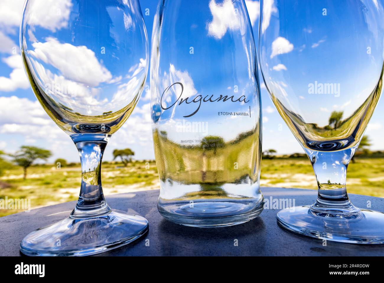 Nahaufnahme von Onguma Flasche und Gläsern mit Fisher's Pan im Hintergrund – Onguma The Fort, Onguma Game Reserve, Namibia, Afrika Stockfoto