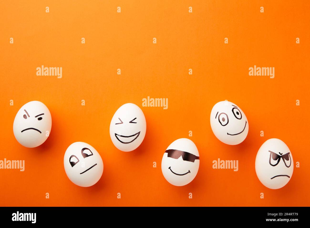 Lustige Ostereier mit verschiedenen Emotionen im Gesicht auf orangefarbenem Hintergrund. Osterkomposition. Draufsicht Stockfoto