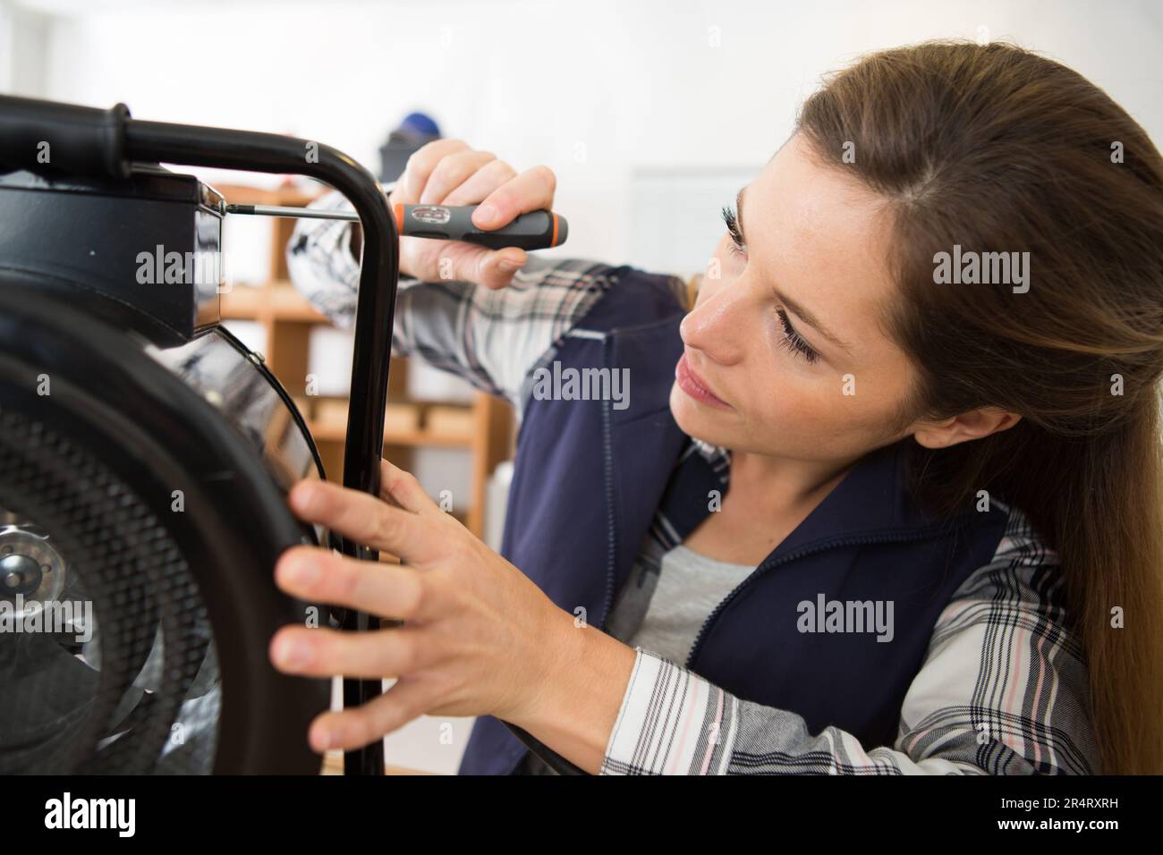 Frau, die einen Schraubenzieher benutzt, um einen elektrischen Ventilator zu reparieren Stockfoto