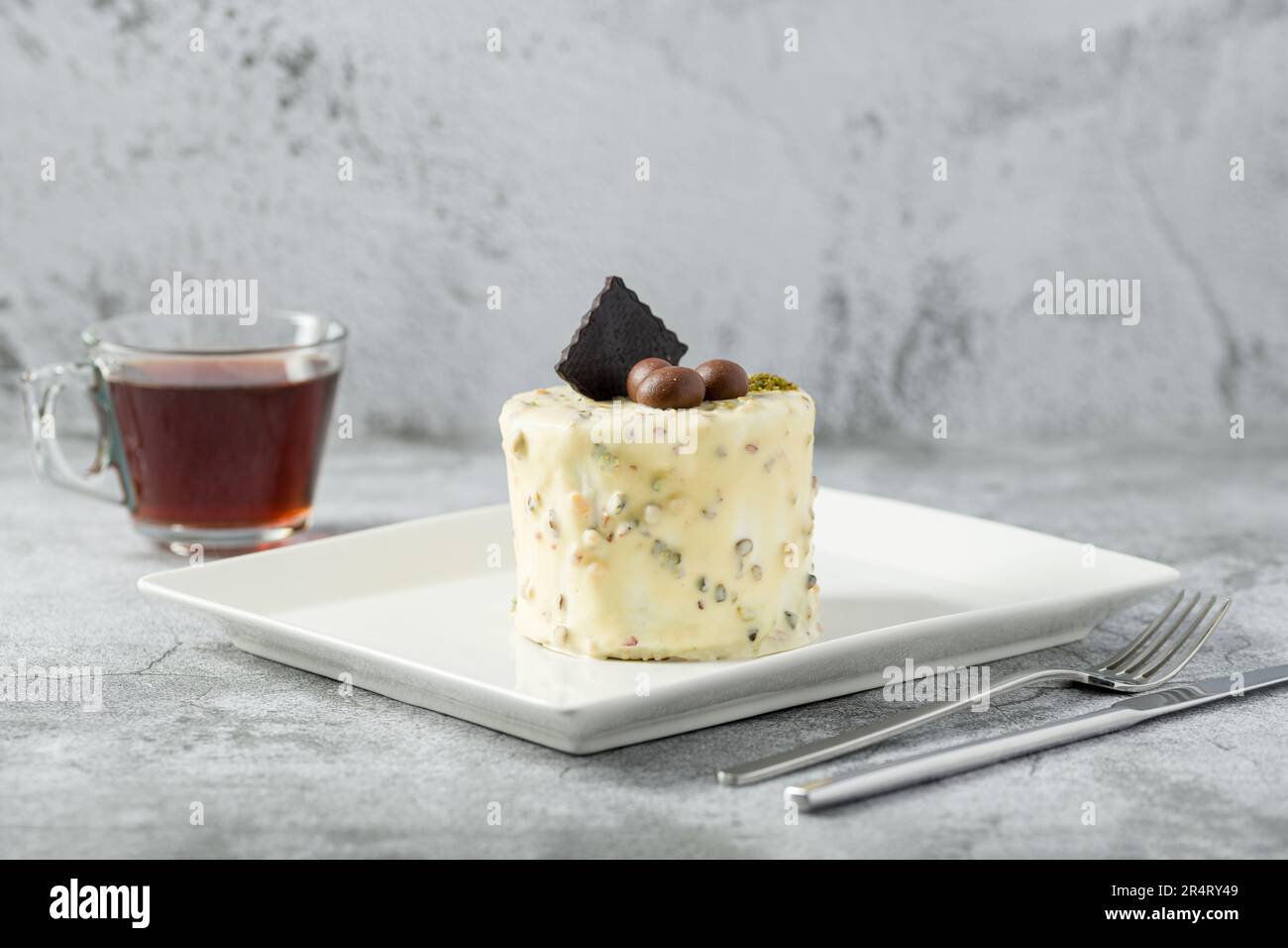Ein-Personen-Minikuchen mit Pistazien und weißer Schokolade auf einem weißen Porzellanteller Stockfoto