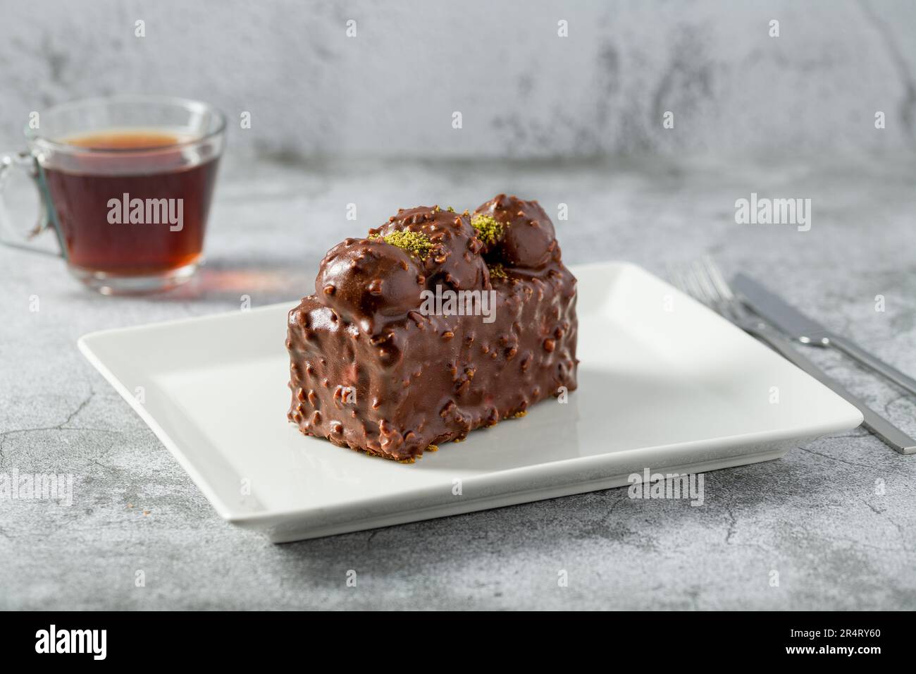 Kuchen mit Profiteroles und Tee auf einem Steintisch Stockfoto