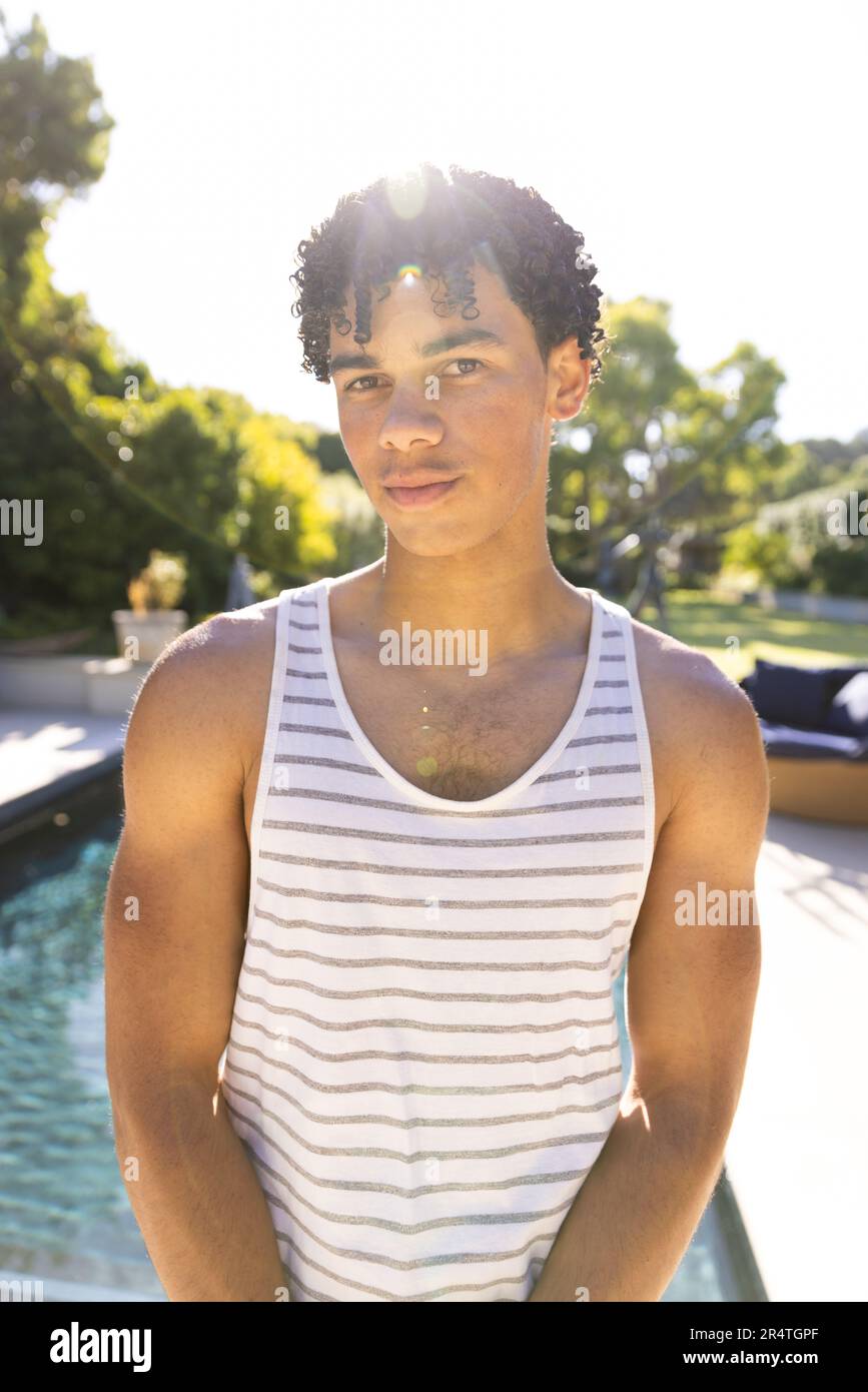 Porträt eines birassischen jungen Mannes, der selbstbewusst am Pool gegen den klaren Himmel steht Stockfoto