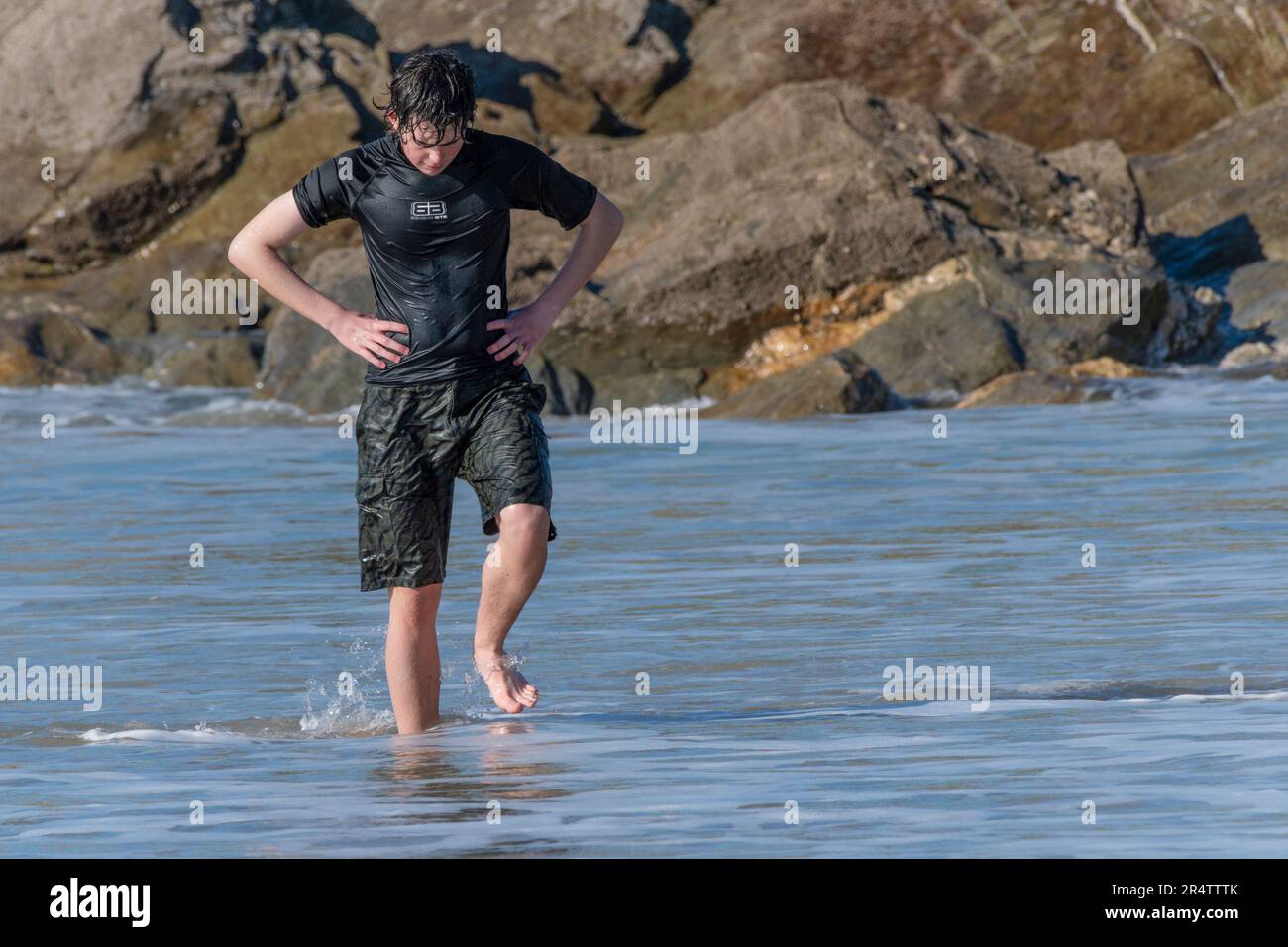 Ein Teenager, der nach dem Schwimmen im Fistral in Newquay in Cornwall in Großbritannien aus dem Meer spazierenging. Stockfoto