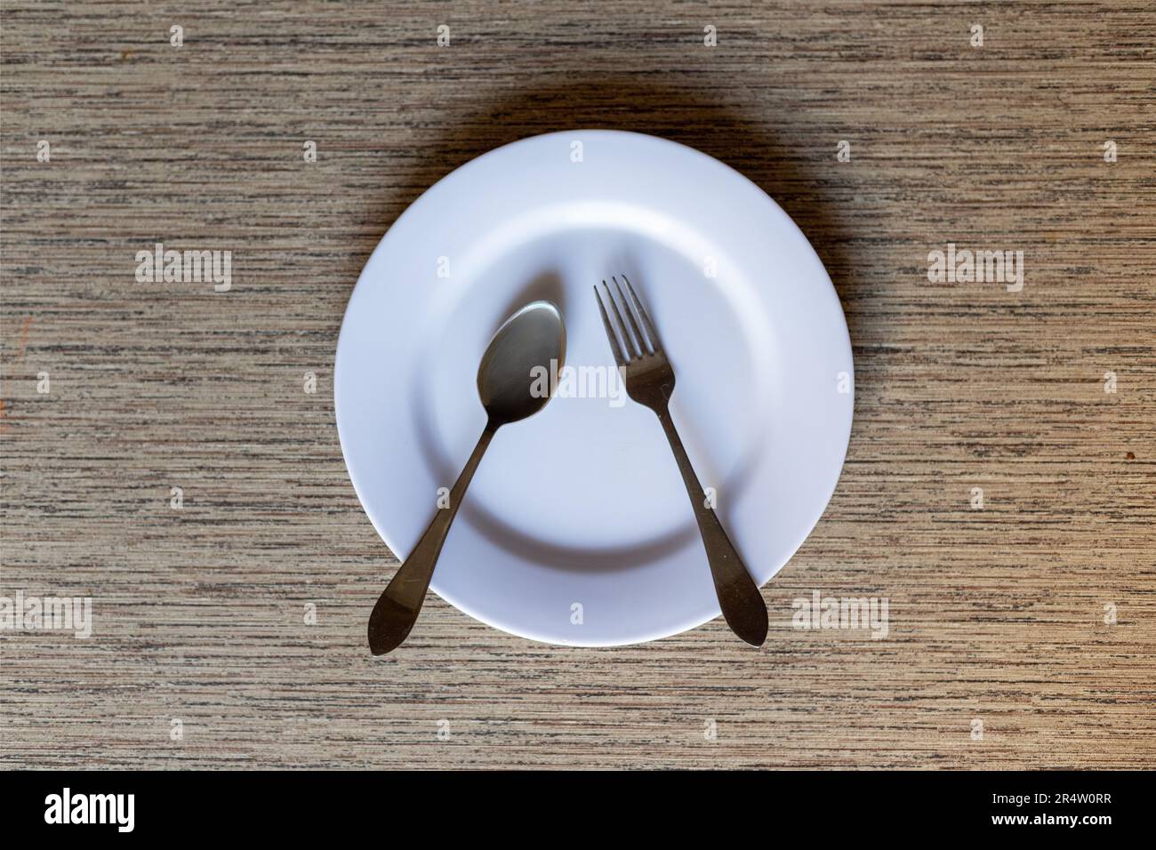 Leerer Teller mit Löffel und Gabel auf dem Tisch. Konzept der Schneidwerkeinstellung. Stockfoto