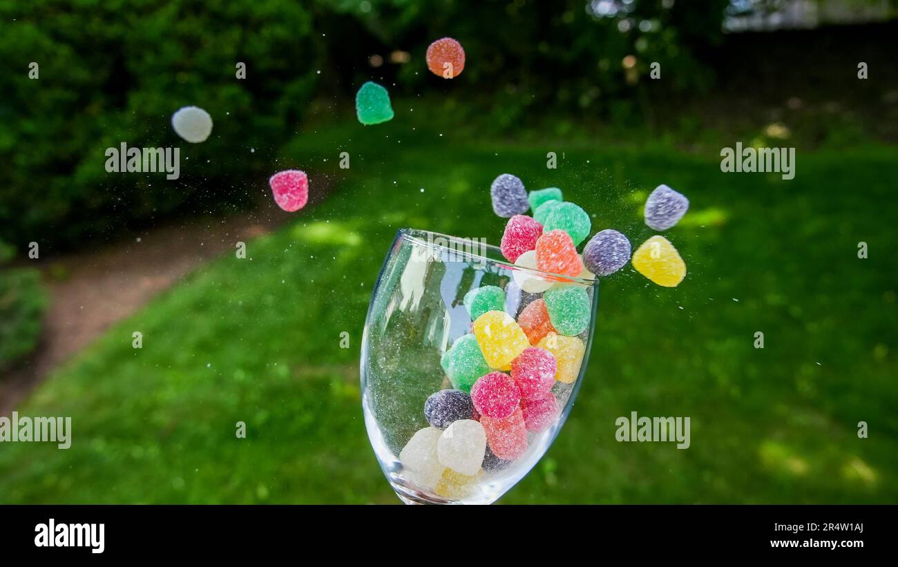Farbenfrohe Süßigkeiten, die aus Glas im Freien herausfliegen Stockfoto