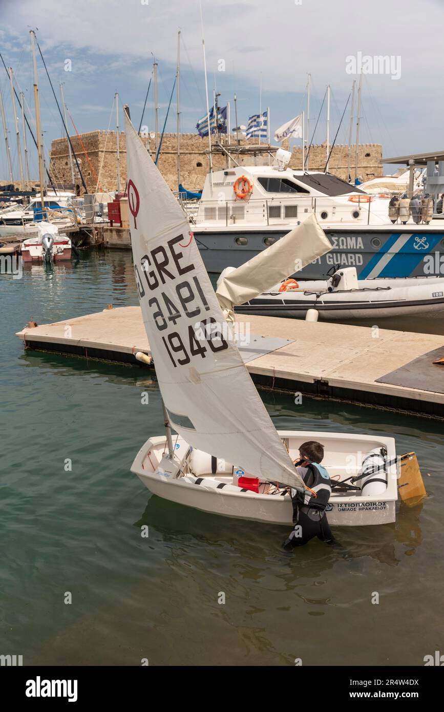 Heraklion, Kreta, Griechenland, Europa. 2023. Junger Junge, der sich auf eine Segelstunde in einem Schlauchboot am alten Hafen in Heraklion, Kreta, vorbereitet. Stockfoto
