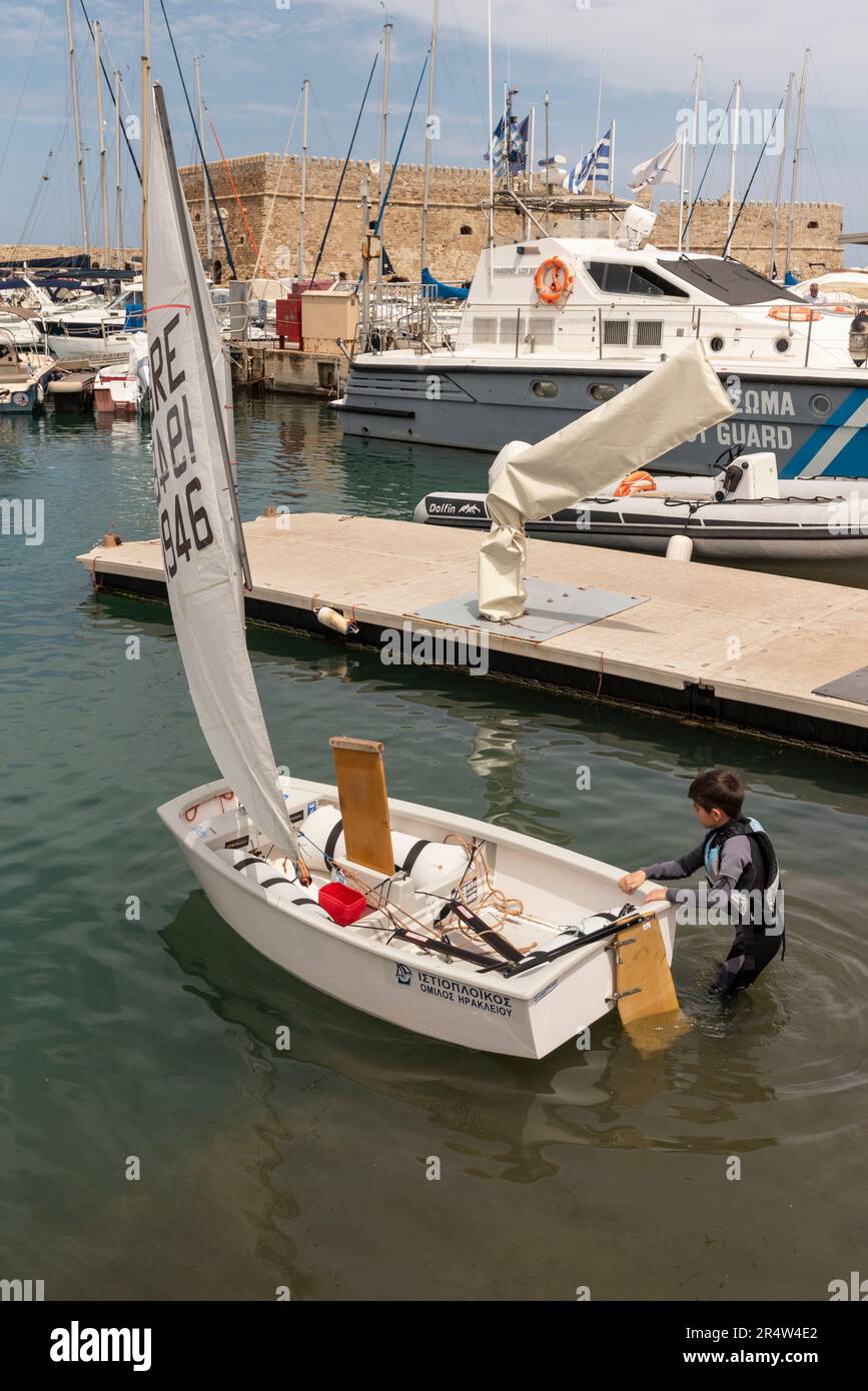 Heraklion, Kreta, Griechenland, Europa. 2023. Junger Junge, der sich auf eine Segelstunde in einem Schlauchboot am alten Hafen in Heraklion, Kreta, vorbereitet. Stockfoto