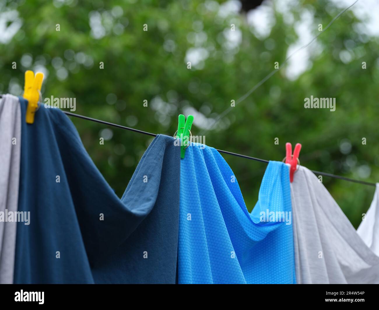 Kleidung hängt an einer Wäscheleine mit bunten Kleidernadeln. Schließen. Stockfoto
