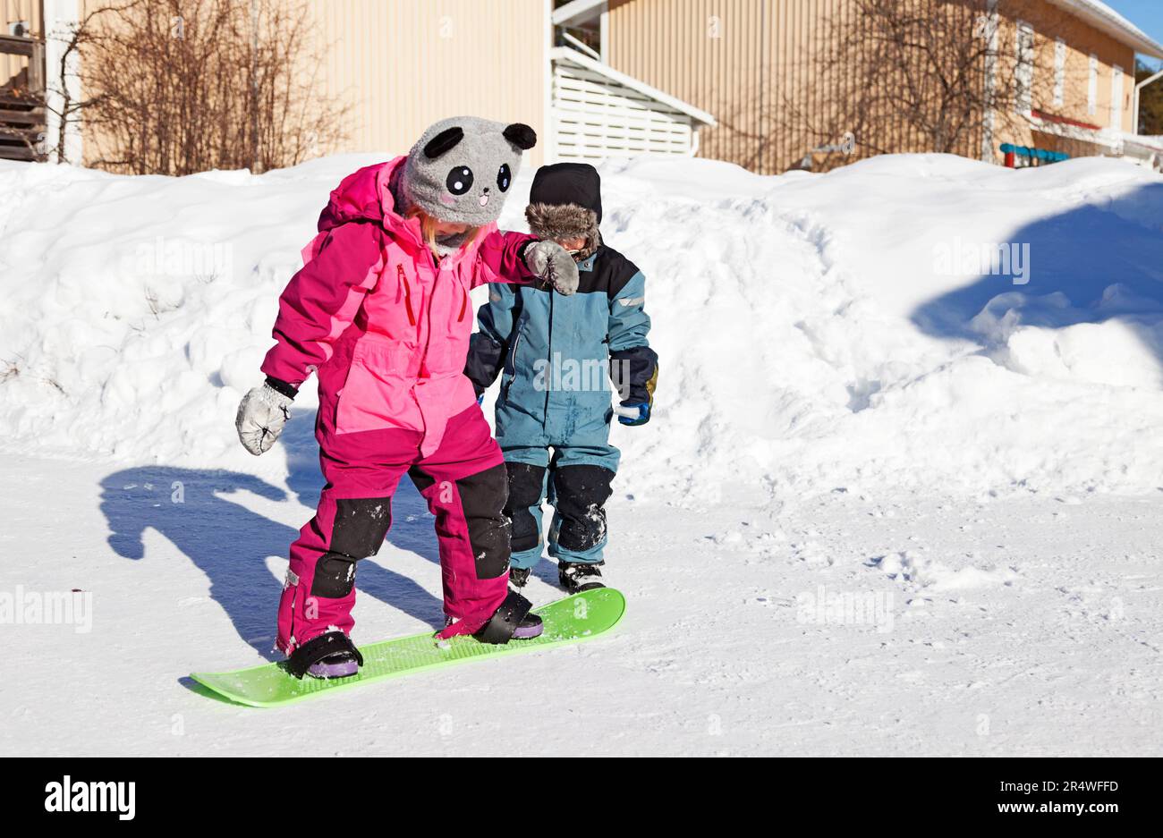 Umea, Norrland Schweden - 11. März 2023: Zwei Geschwister spielen mit Snowboard im Schnee Stockfoto