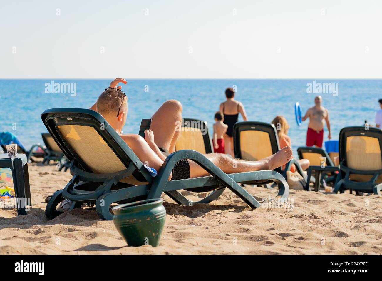 Antalya; Türkei-Oktober 29; 2021: Ein Mann mit Sonnenbrille liegt auf einer Liege und benutzt sein Handy beim Sonnenbaden am Strand. Antalya ist beliebt Stockfoto