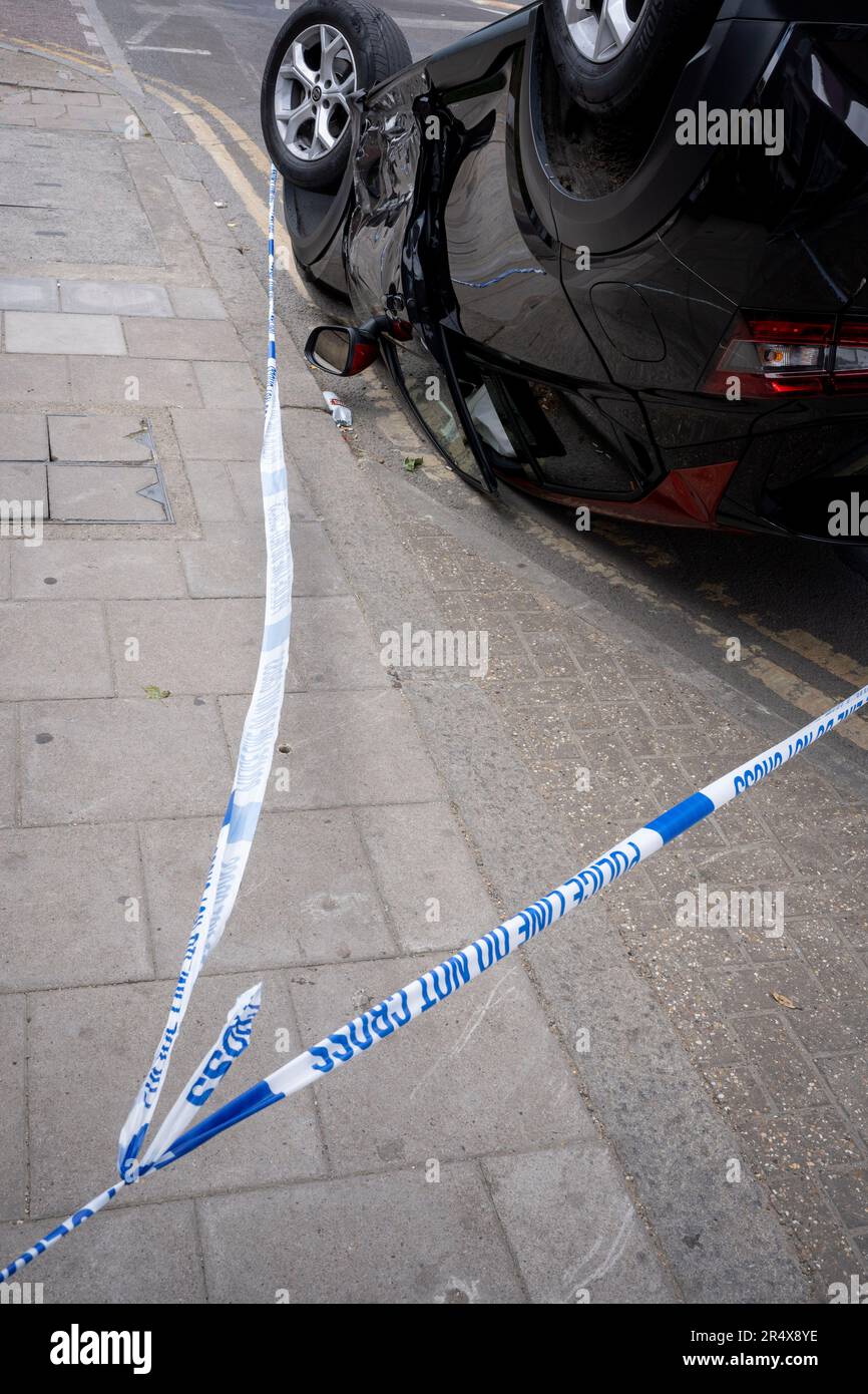 Das Polizeivideo umgibt die Folgen eines Autounfalls, bei dem ein umgestürzter Nissan-Heck an einer Bushaltestelle zwischen Brixton und Camberwell auf der Coldharbour Lane am 30. Mai 2023 in London, England, bleibt. Stockfoto