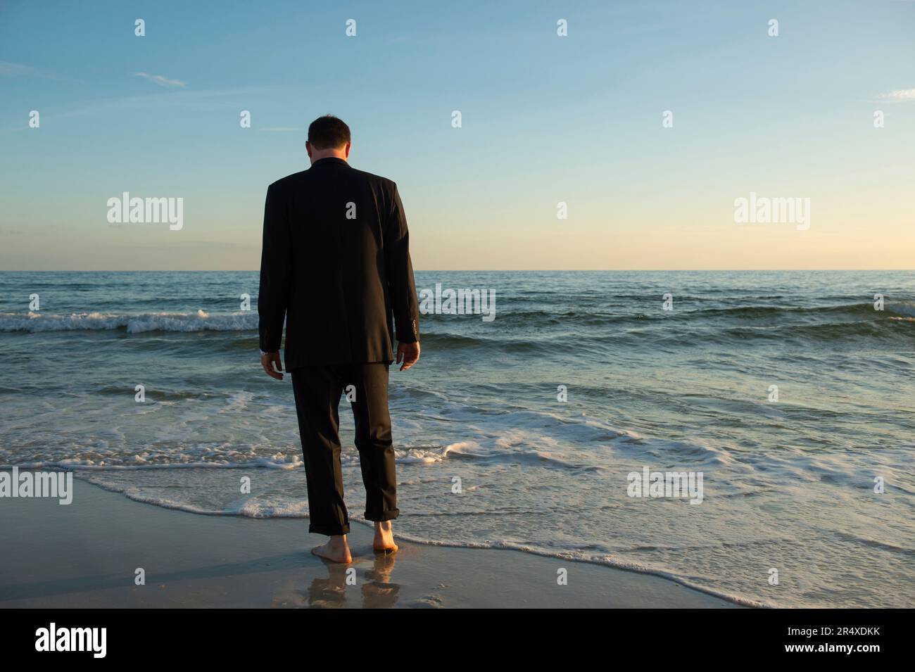 Ein Mann im Anzug geht ins Meer; Panama City Beach, Florida, Vereinigte Staaten von Amerika Stockfoto