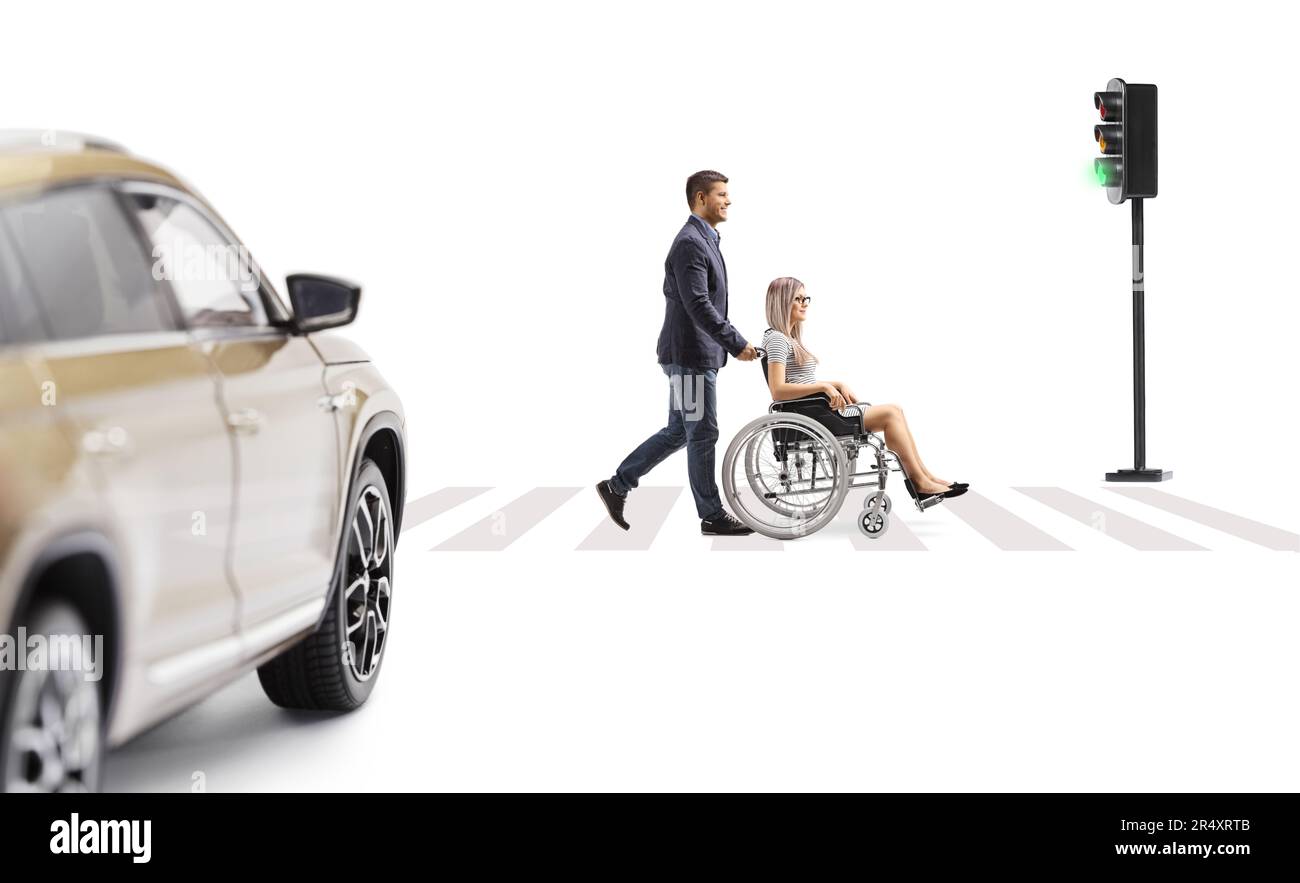 Profilaufnahme über die gesamte Länge eines jungen Mannes, der eine junge Frau im Rollstuhl an einem Fußgängerübergang schubst, isoliert auf weißem Hintergrund Stockfoto
