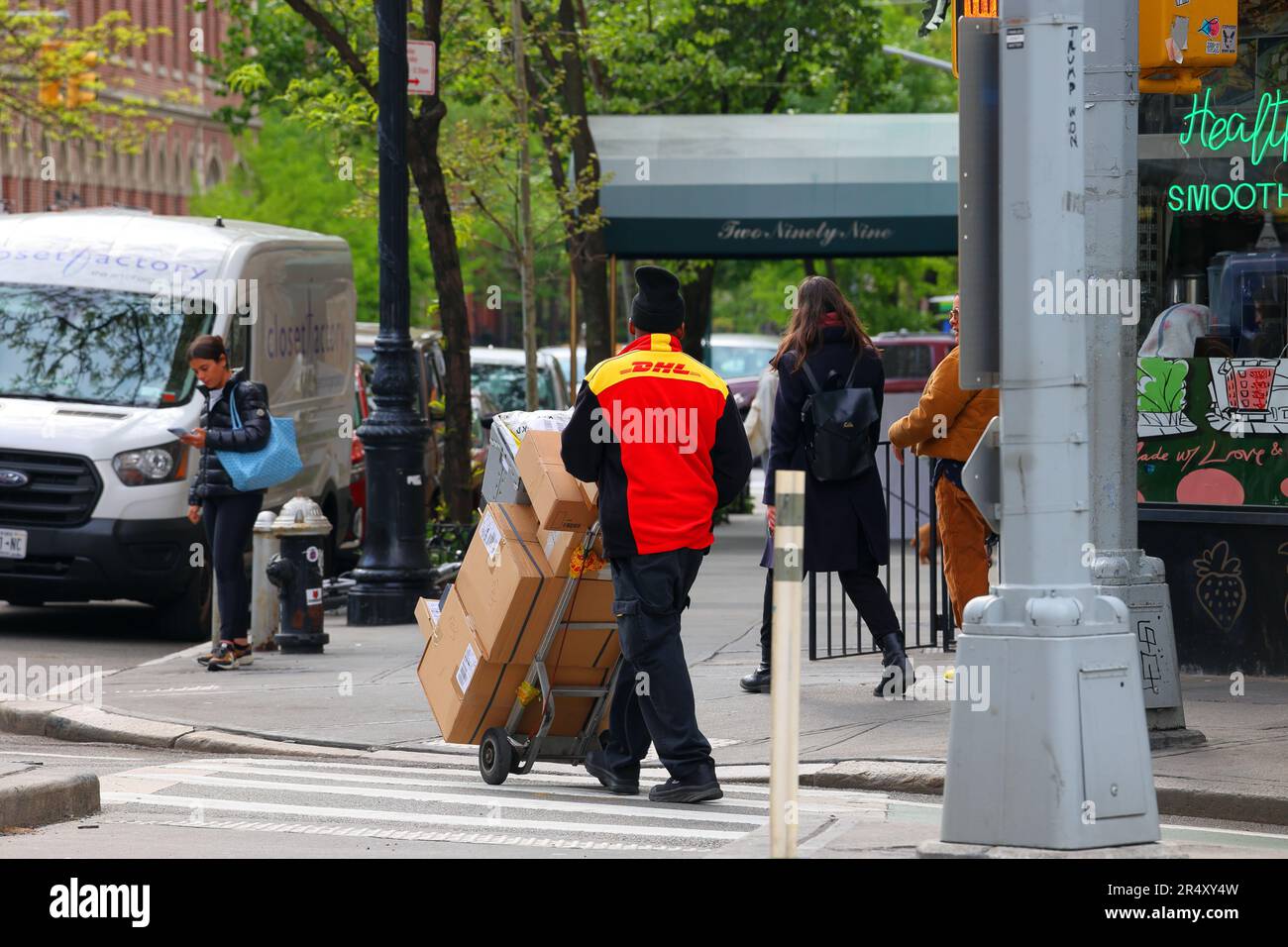 Ein DHL-Zusteller mit einem Handwagen voller Pakete in New York City. Stockfoto