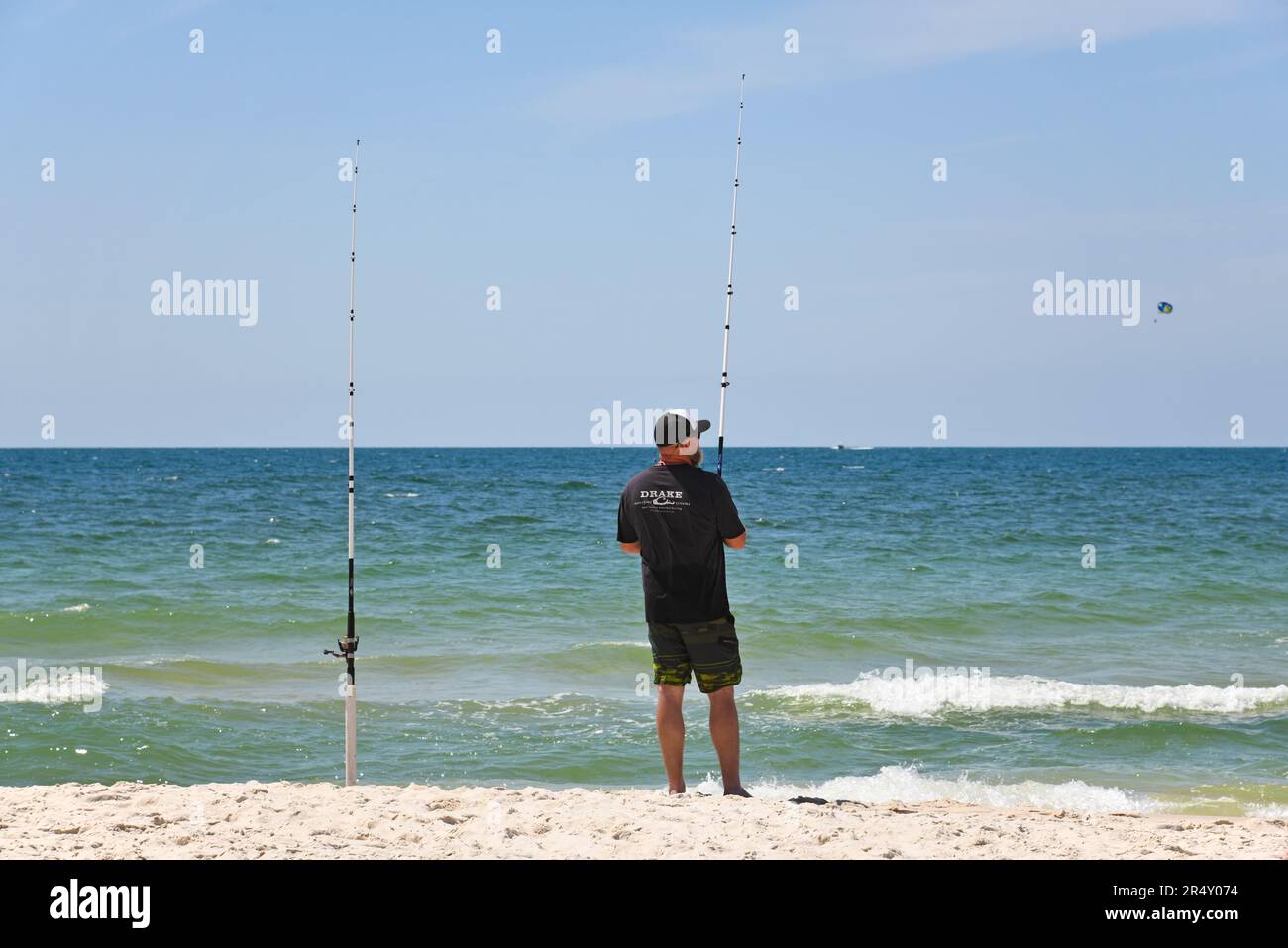 GULF SHORES, AL / USA - 3. Mai 2023: Young man Fishing während Sie einen wunderschönen sonnigen Tag am Gulf Shores Beach am Golf von Mexiko genießen Stockfoto
