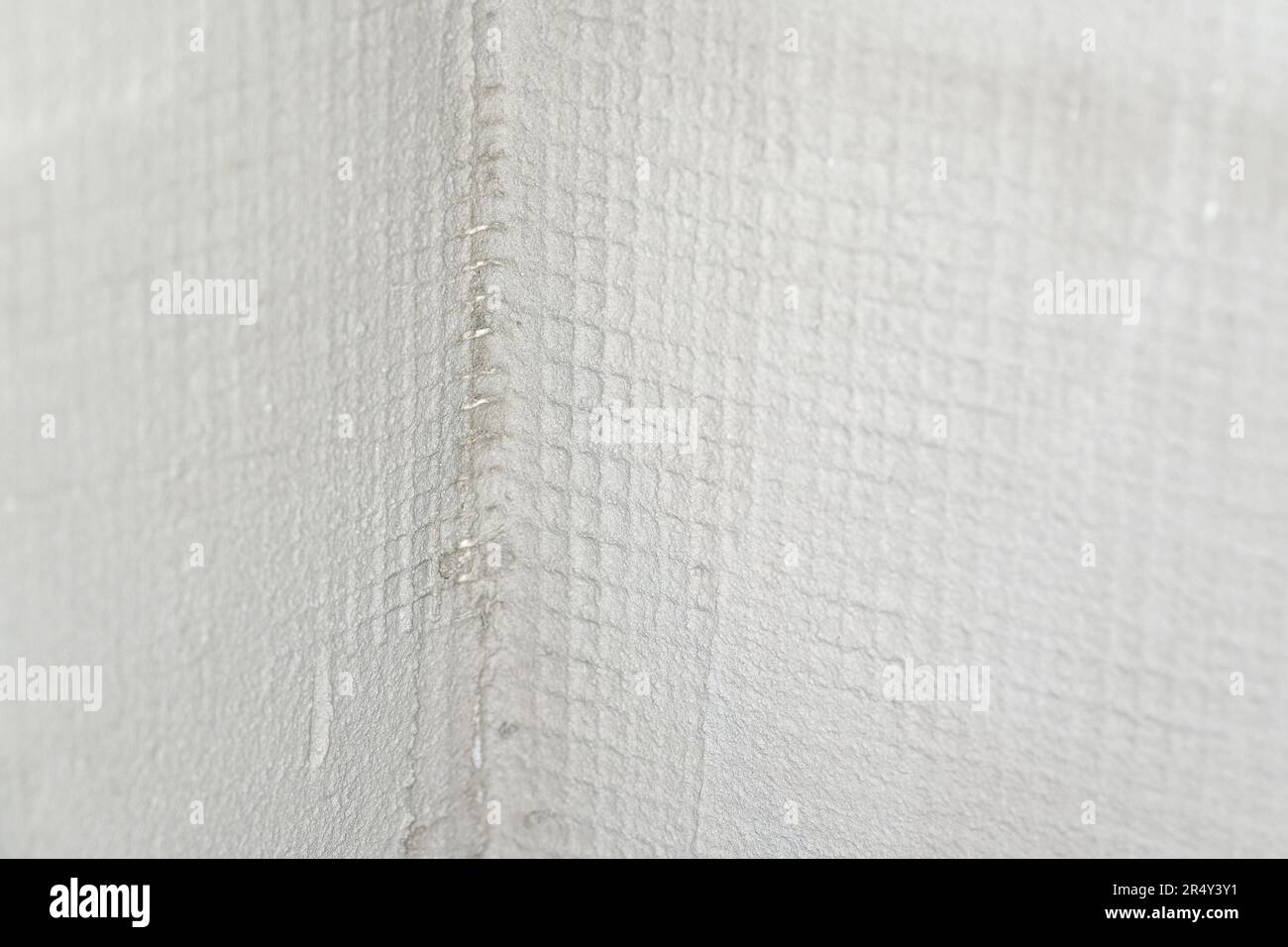 Blanke Wand auf einer Neubaustelle mit Kunststoff-Verstärkungsnetz unter Mörtel, Nahaufnahme Stockfoto