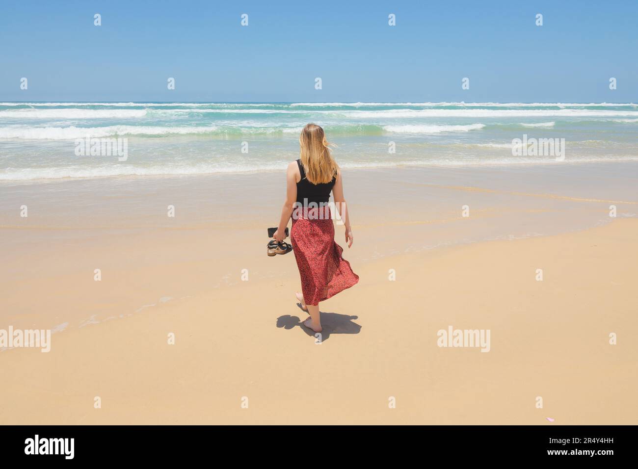 Eine junge blonde Touristin genießt Urlaubszeit am Strand, Surfers Paradise, Gold Coast, Queensland an einem sonnigen Sommer da Stockfoto