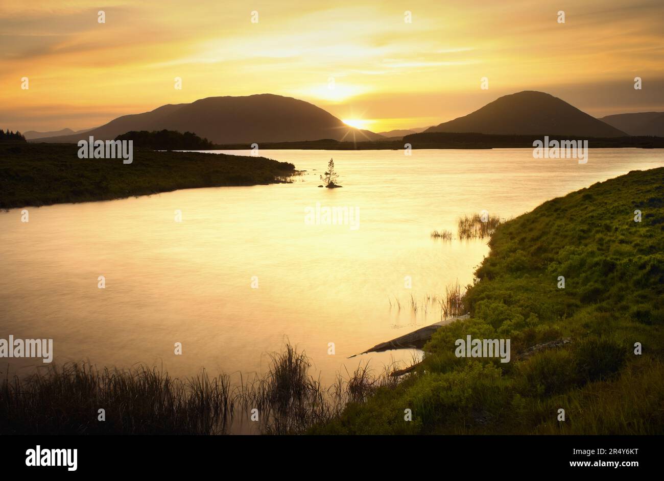 Wunderschöne goldene Sonnenuntergangslandschaft mit See und Bergen im Connemara National Park in County Galway, Irland Stockfoto
