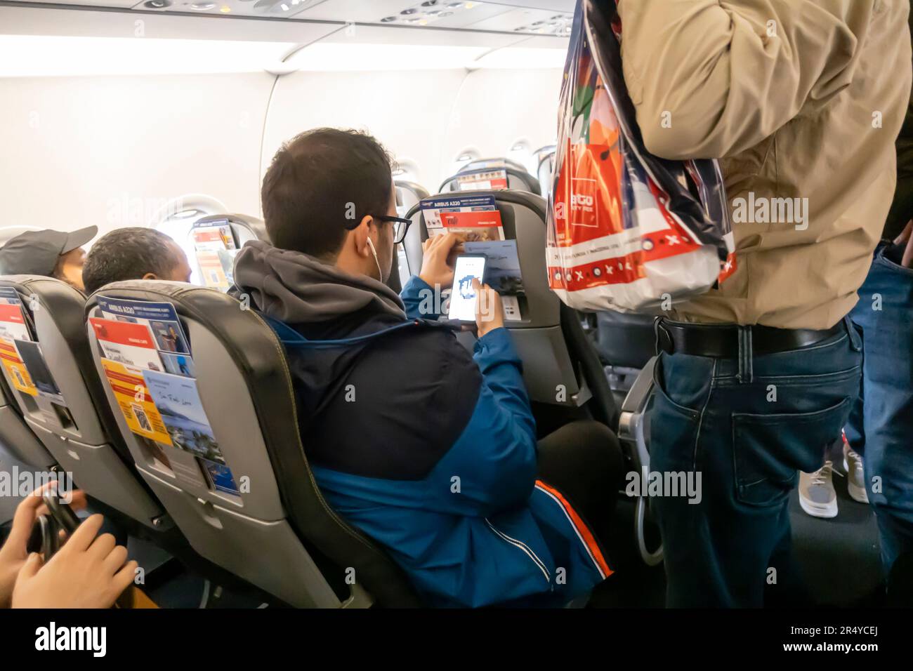 Passagier mit Smartphone auf dem Sitz des Flugzeugs beim Einsteigen in den Airbus A 320 Stockfoto